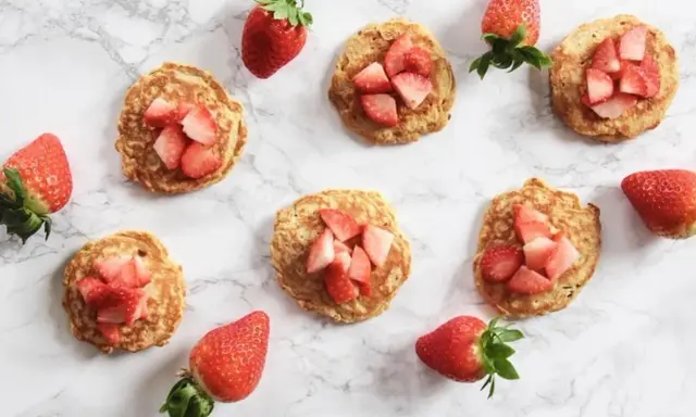 Små proteinpannkakor toppade med färska jordgubbar. Perfekt för en snabb och nyttig frukost eller mellanmål, som en mugcake proteinpulver.