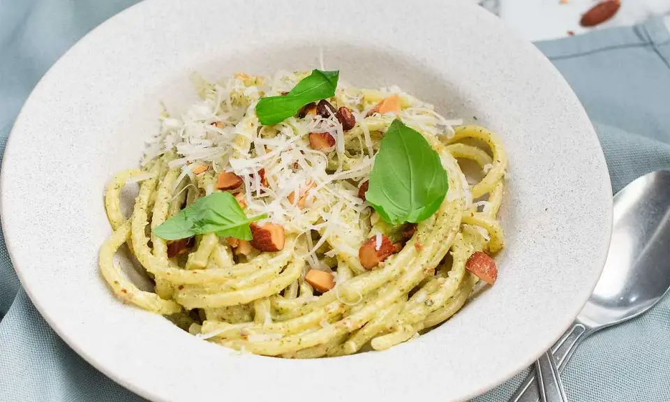 En portion krämig pasta med pesto, toppad med riven ost, nötter och basilika. Perfekt spagetti koktid för en snabb och god måltid.