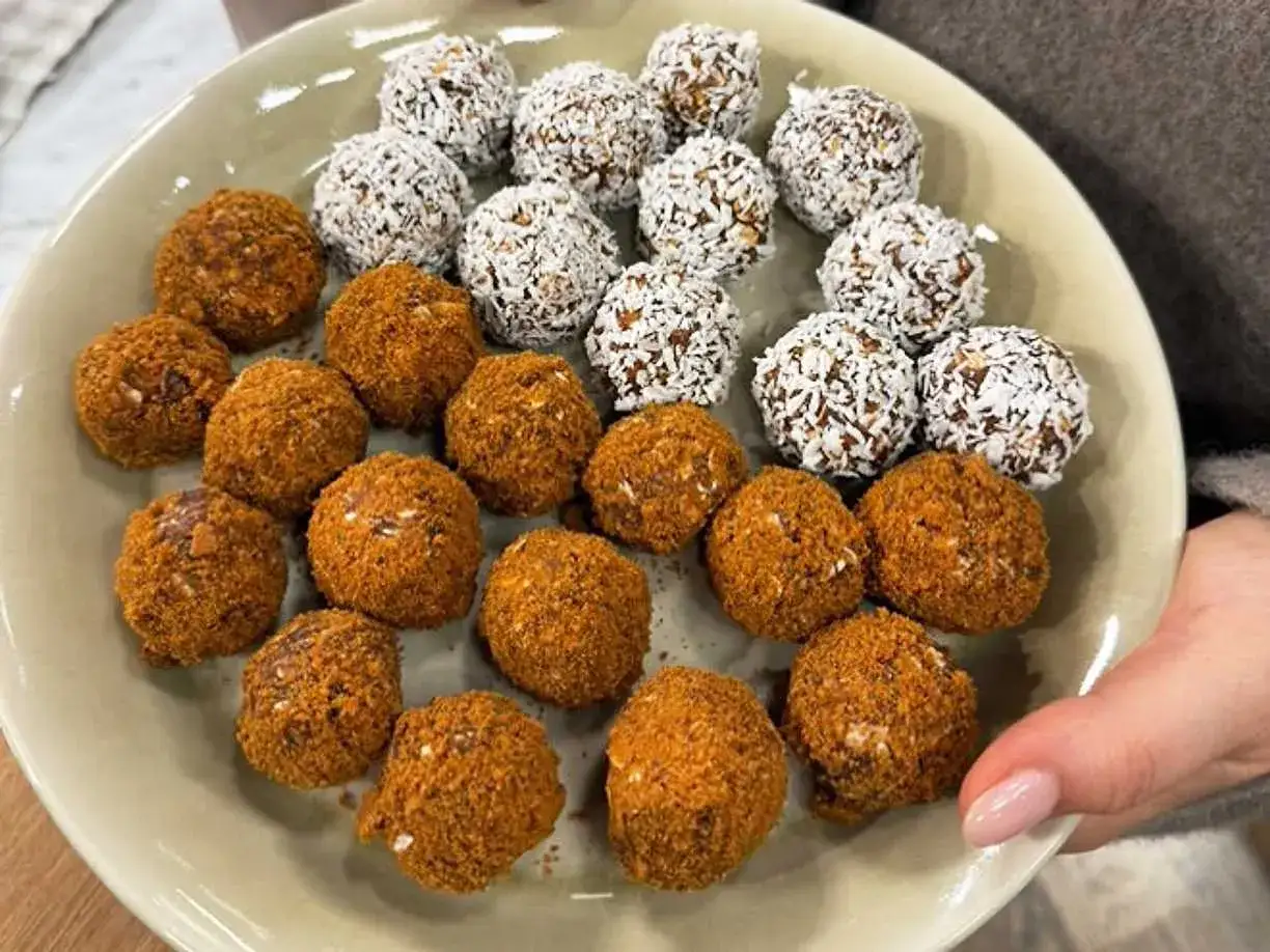 En tallrik med hemgjorda pepparkaksbollar och dadlar, vissa rullade i kokos.