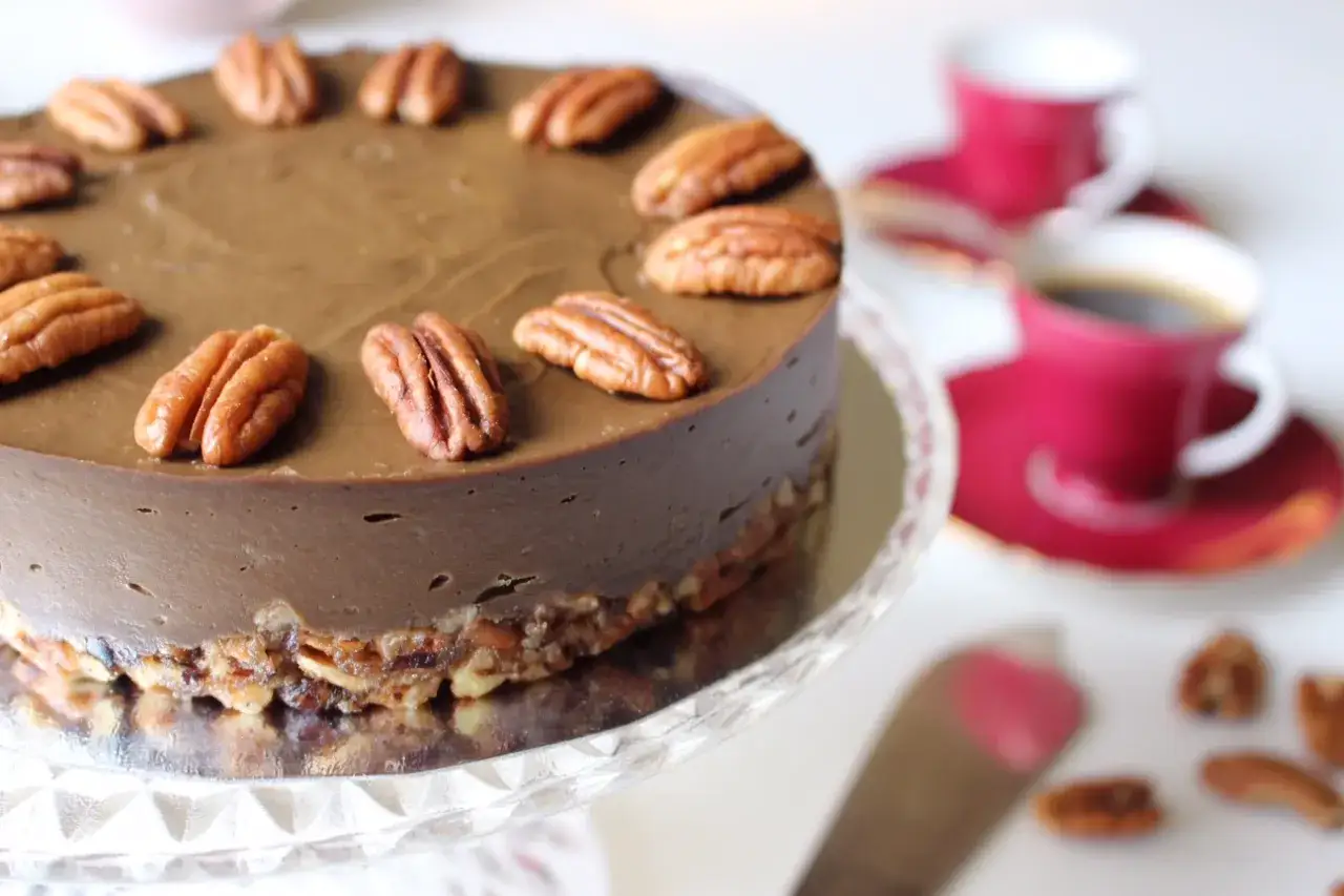 En l&auml;cker raw t&aring;rta med chokladsmak, toppad med pekann&ouml;tter. Serveras med kaffe och en spatel.