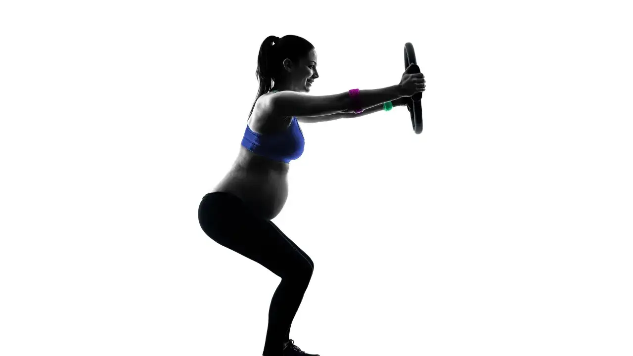 Gravid kvinna tr&auml;nar med pilatesring.