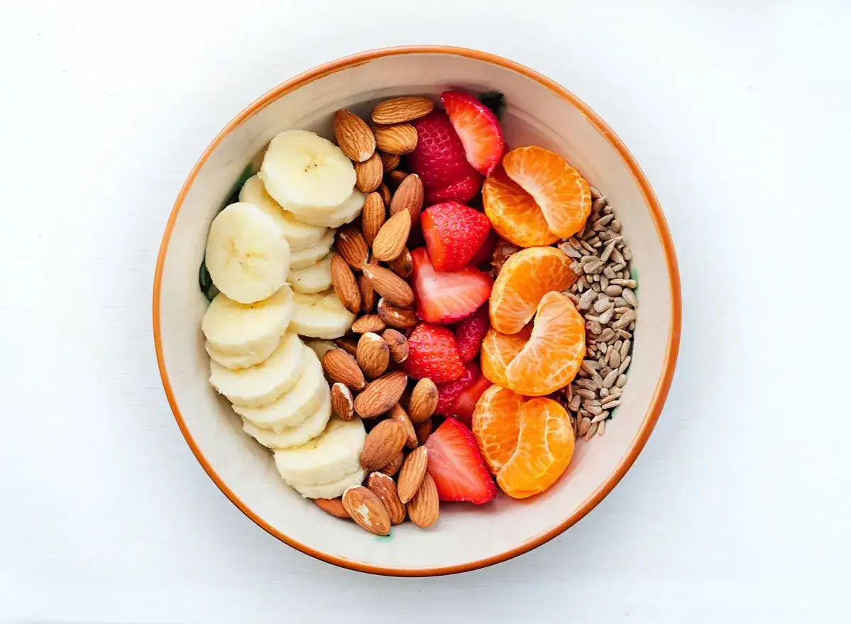 Frukostskål med banan, jordgubbar, clementiner, solrosfrön och mandlar. Mandlar nyttigt för en energifylld start!