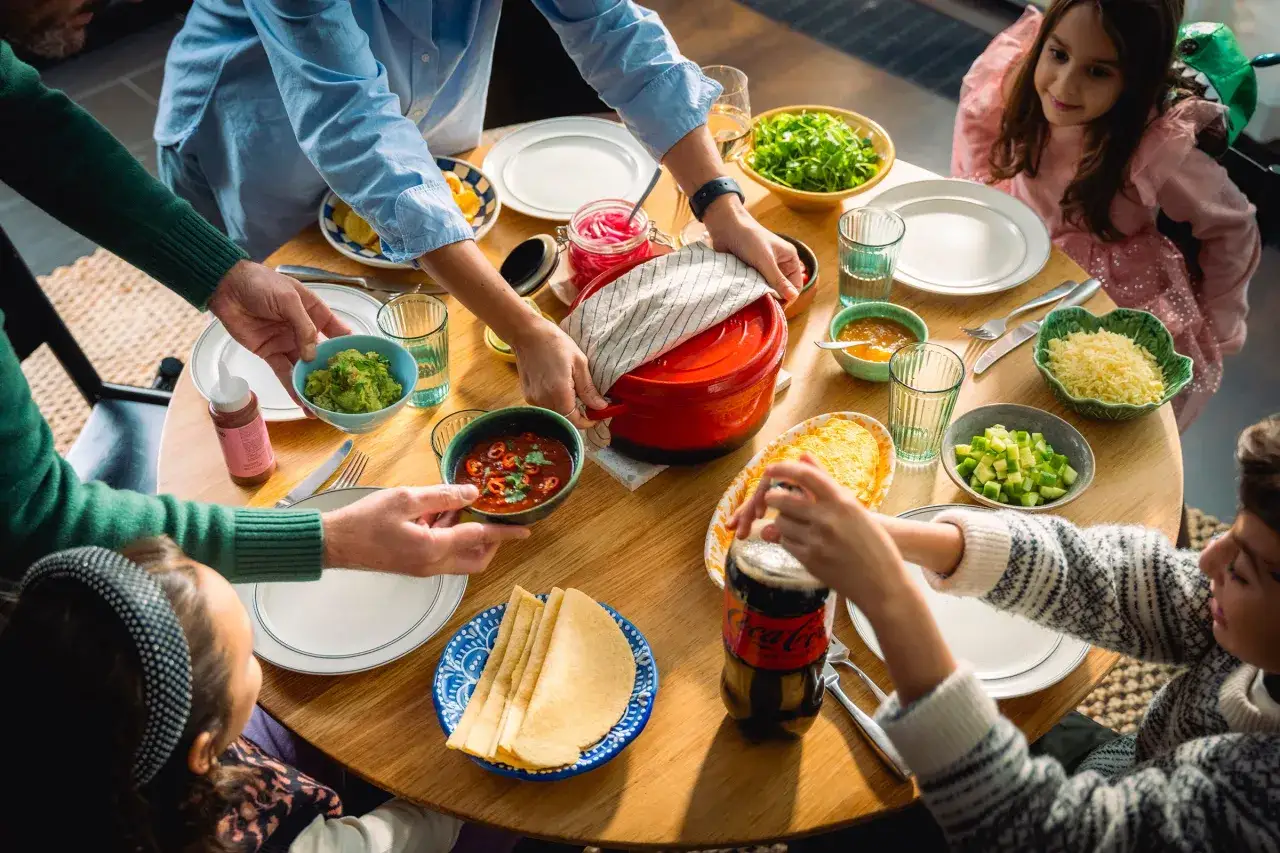 Familjen samlas runt bordet för en mysig middag med nyttig vardagsmat som guacamole, salsa och sallad.