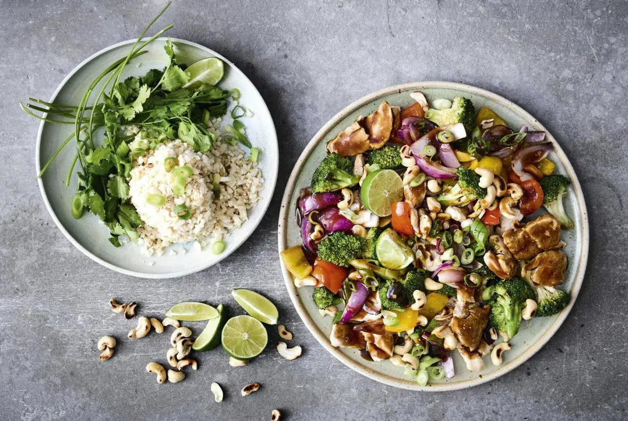 Tv&aring; tallrikar med asiatisk kycklingwok och ris. Enkel nyttig mat med broccoli, paprika, cashewn&ouml;tter och lime.