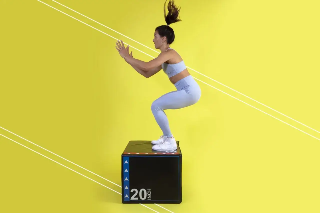 Kvinna i tr&auml;ningskl&auml;der utf&ouml;r en box jump p&aring; en svart box med texten 