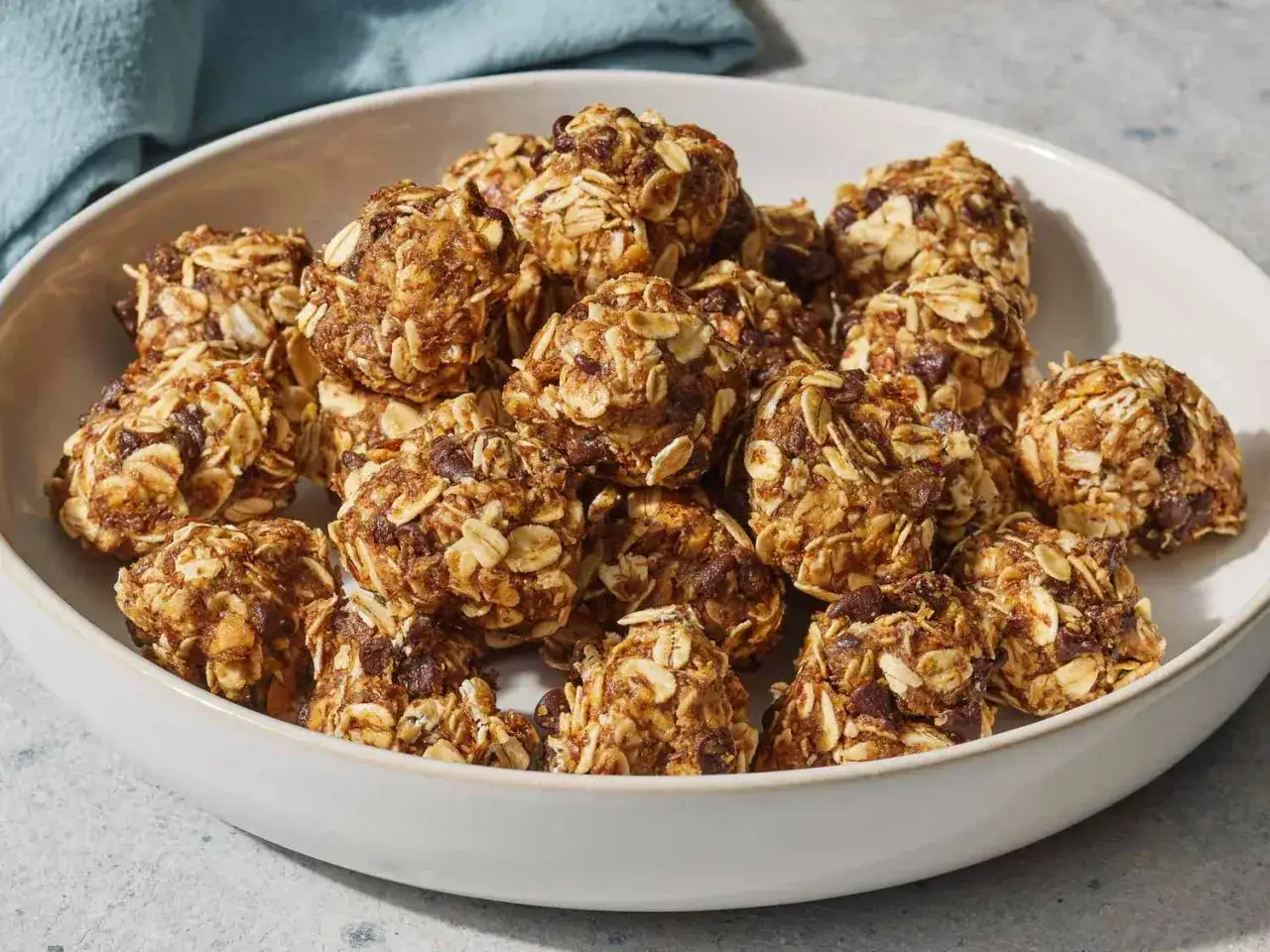 En sk&aring;l med hemgjorda energibollar, perfekta som mellanm&aring;l protein. De ser mumsiga ut med havre och chokladbitar.