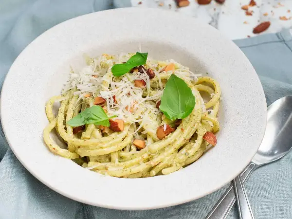 En portion krämig pasta med pesto, toppad med riven ost, nötter och basilika. Perfekt spagetti koktid för en snabb och god måltid.